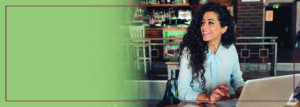 Photo of woman with long dark curly hair sitting at laptop computer.