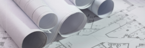 Photo showing rolled architectural drafts on top of unrolled architectural drafts.
