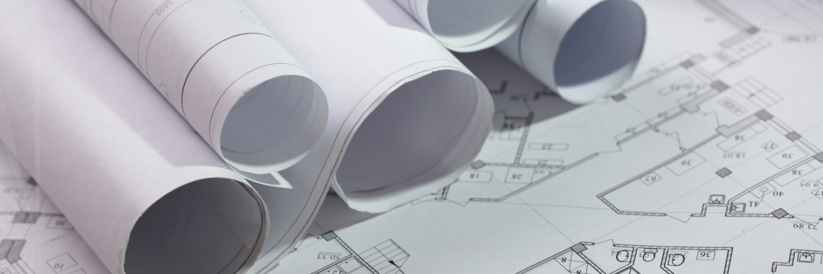 Photo showing rolled architectural drafts on top of unrolled architectural drafts.